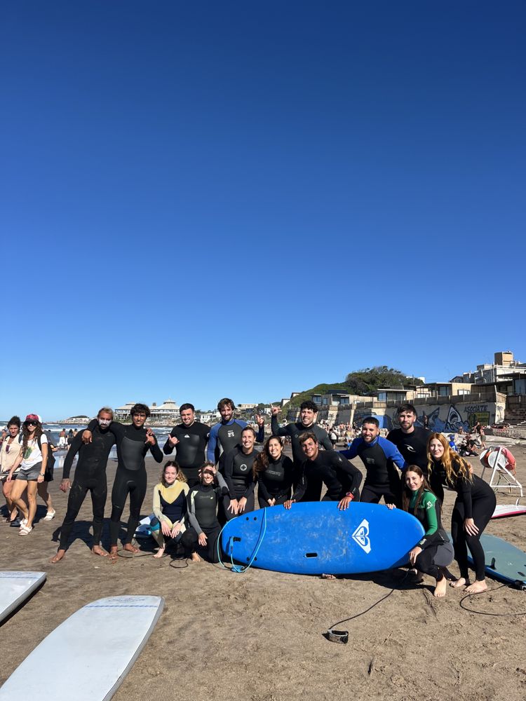 Grupo grande de alumnos con una tabla en la playa