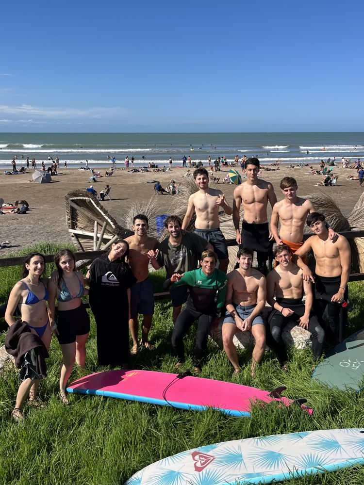 Grupo grande de alumnos en el pasto frente a la playa