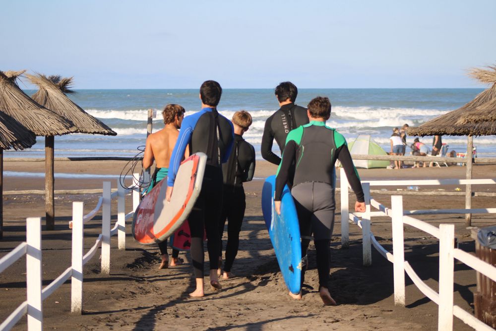 Alumnos caminando hacia el mar con sus tablas