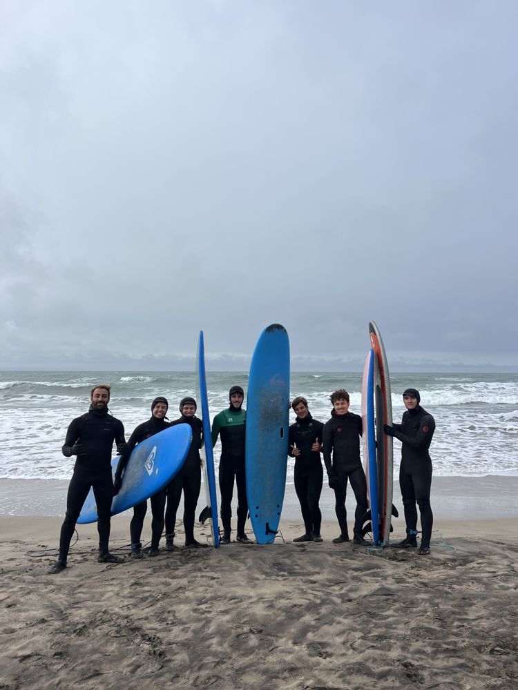 Alumnos posando con tablas en la playa