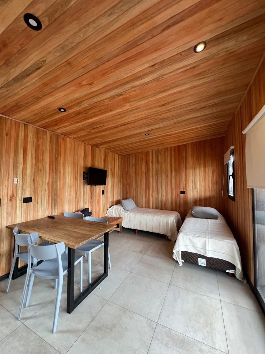 Ambiente con dos camas, mesa y tele