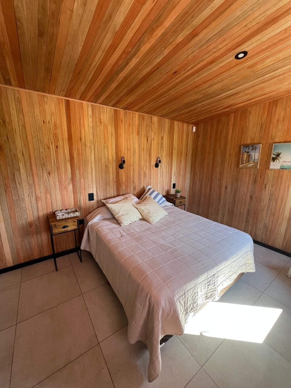Habitación con cama matrimonial y cuadros de playa