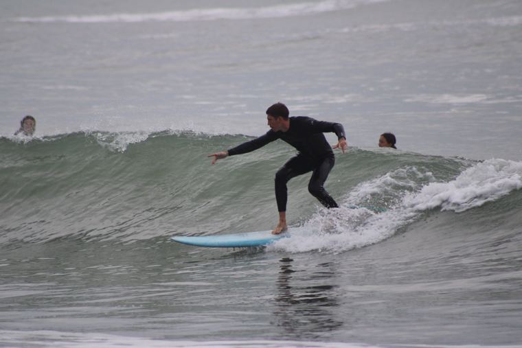 Alumno surfeando una ola verde