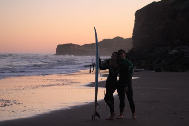 Pareja abrazada con la tabla al atardecer