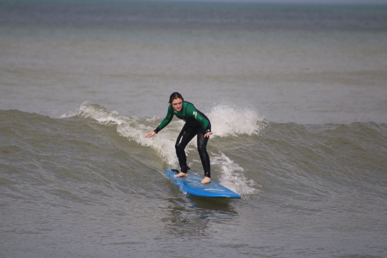 Alumna surfeando con traje verde