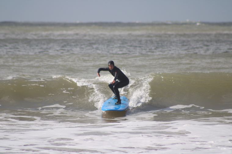 Alumna con capucha surfeando de frente